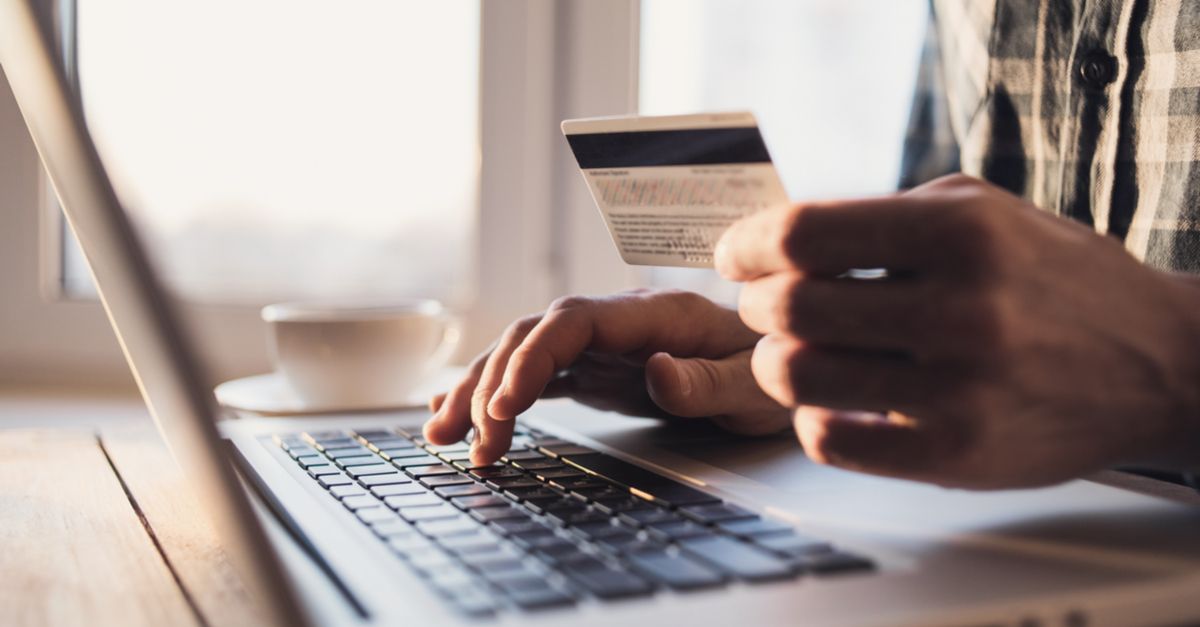 Man holding credit card in front of laptop computer