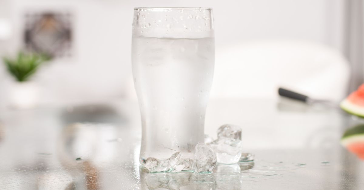 A glass of cold water with ice on a table.