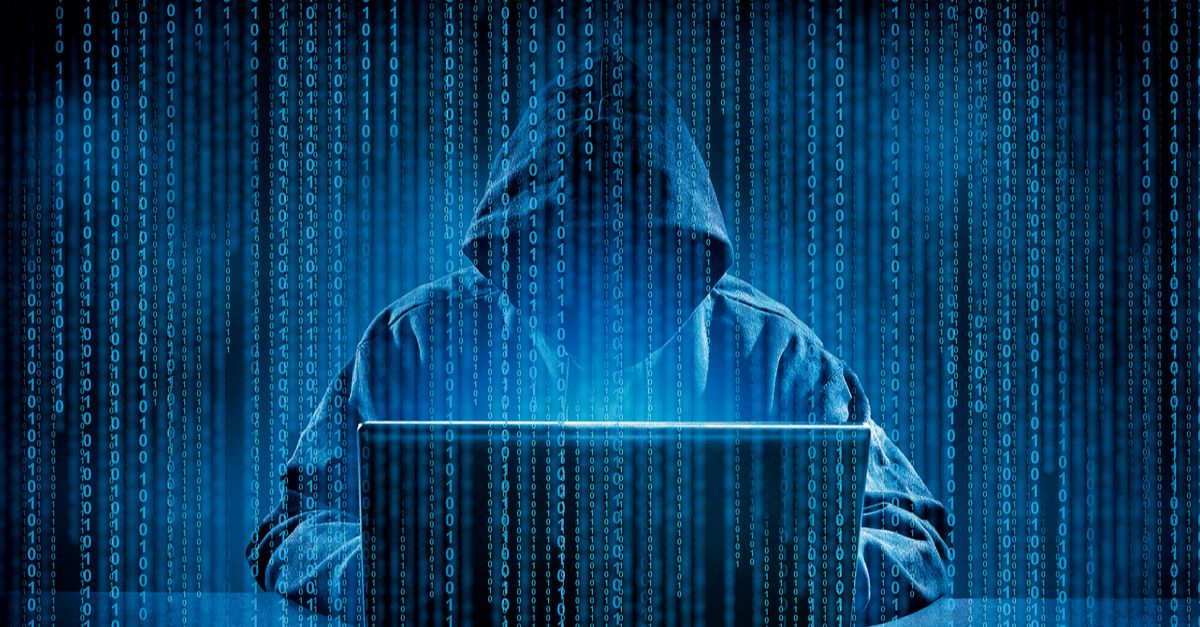 Person wearing a hoodie sits in front of a laptop computer