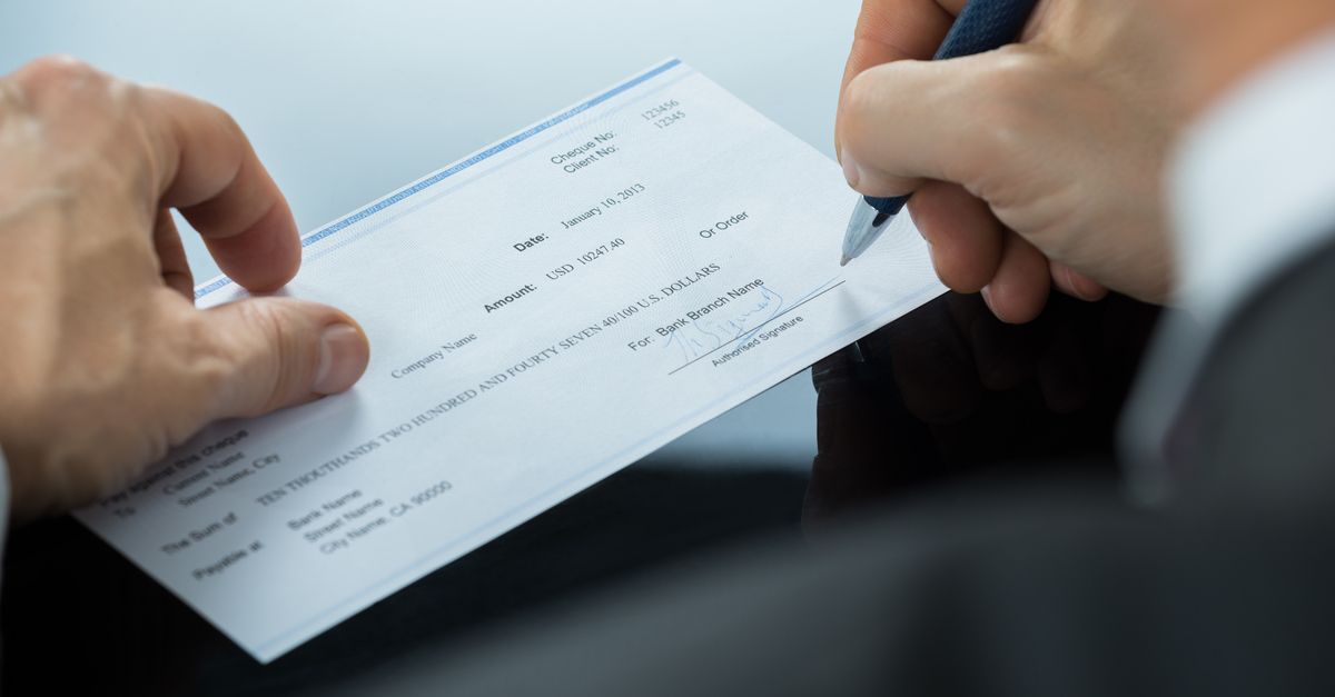 Close-up of someone signing a check.