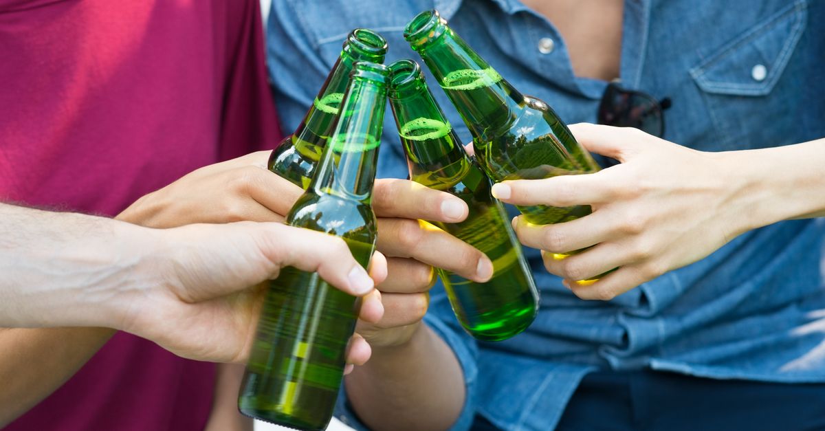 Four people clinking beer bottles.