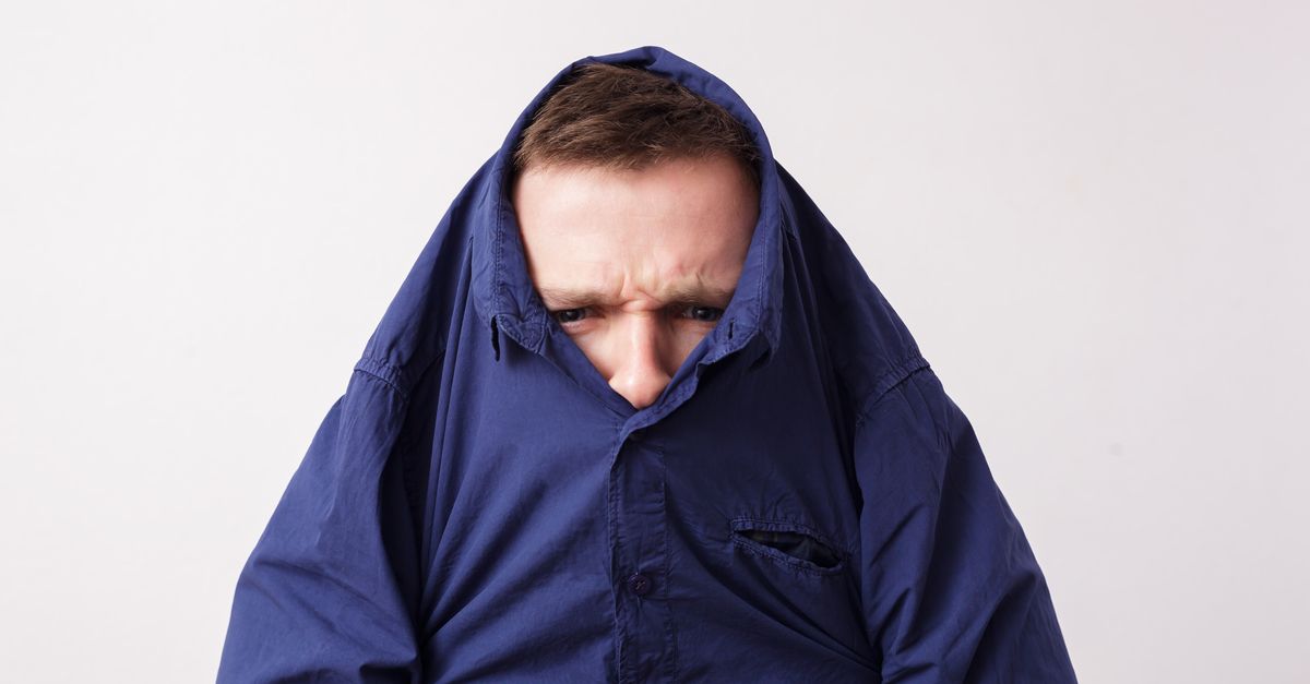 Man with head stuck in blue collared shirt