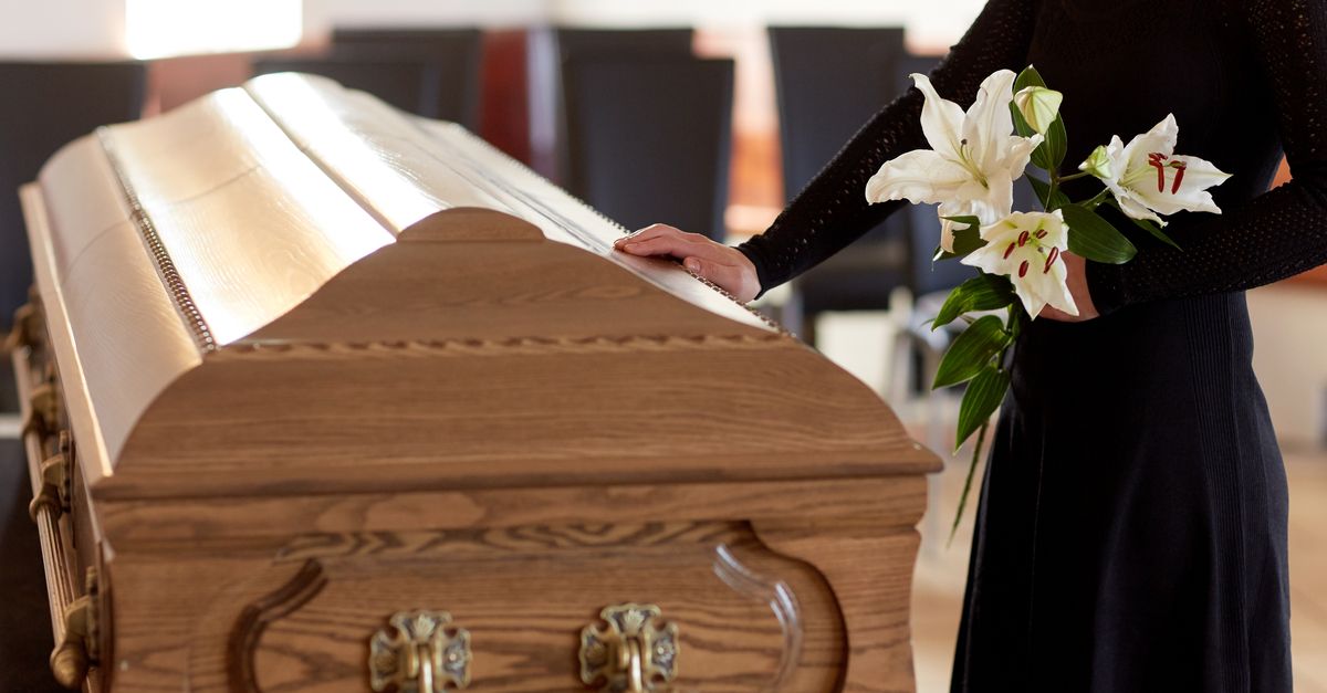 woman with white lily flowers and coffin at funeral in church
