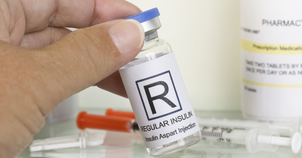 Insulin bottle with syringes in background