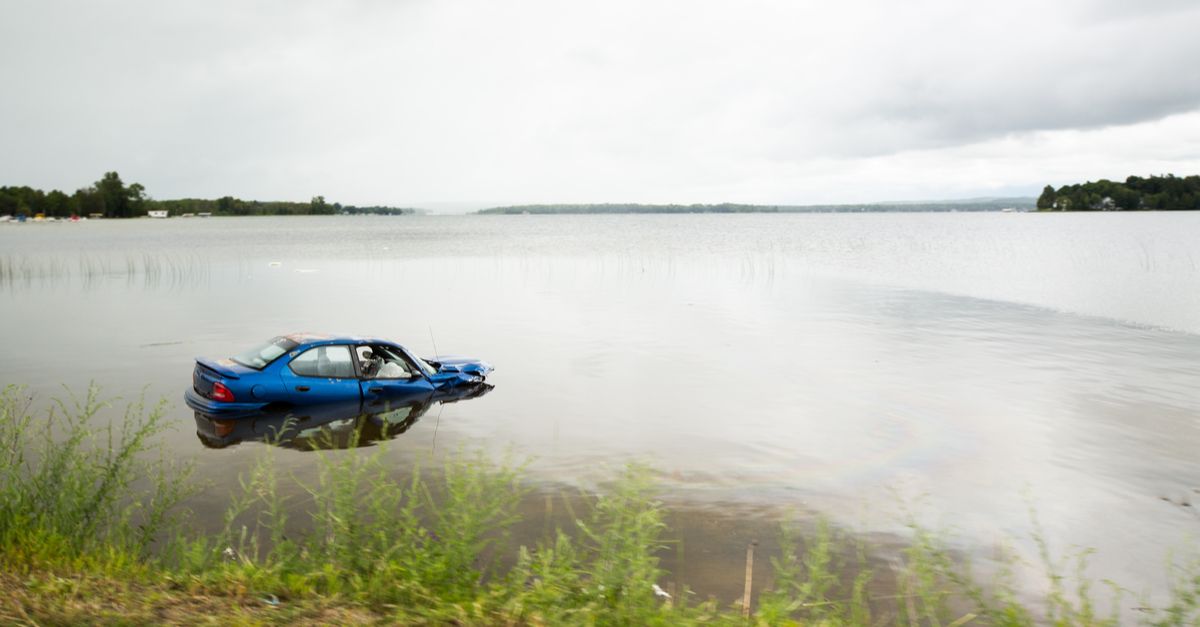 Blue car halfway submerged in lake