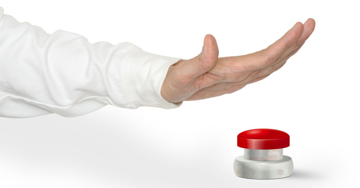 A man pushing a big red start stop alarm panic button with the palm of his hand.