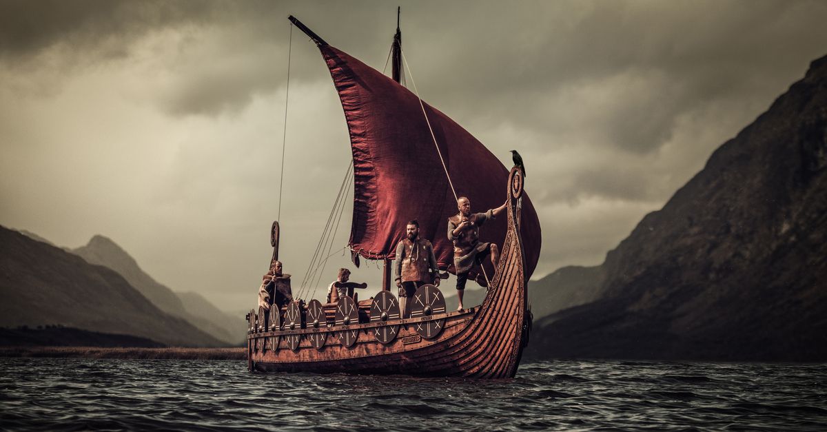 A group of Vikings floating on the sea on Drakkar with mountains on the background.
