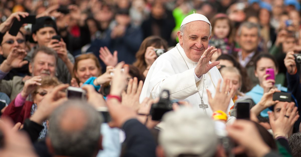Smiling Pope Francis surrounded by a crowd.
