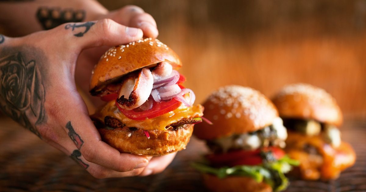 Hands holding a hamburger.
