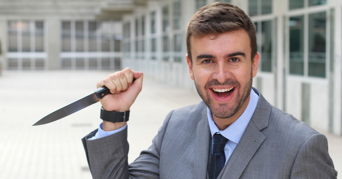 Happy man in business suit wielding a knife.