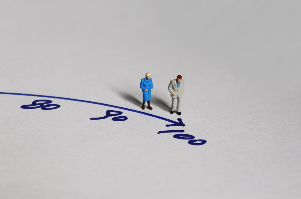 Old,Couple,Miniature,Standing,Before,The,Number,100.