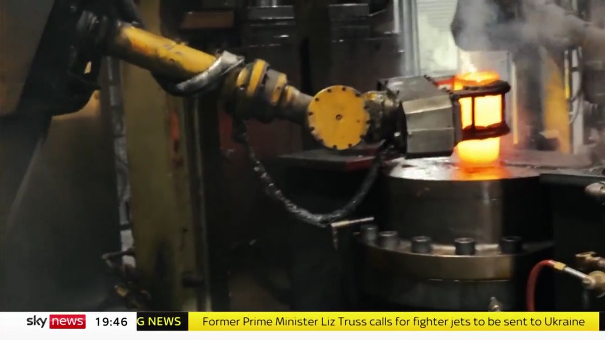 A machine is holding a tube of hot red materials in a cylinderical shape. You can see a gear beneath the platform the materials are on. At the bottom, it says "Former Prime Minister Liz Truss calls for fighter jets to be sent to Ukraine."