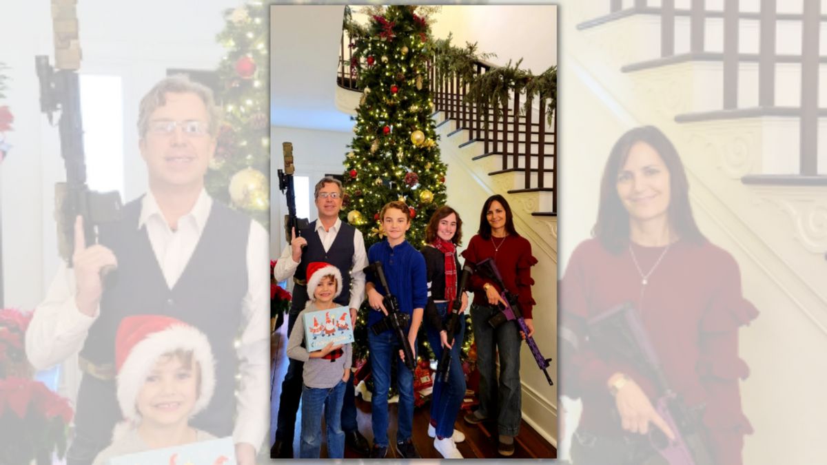 Five white people stand in front of a Christmas tree. Four are holding guns, while the youngest is holding a Christmas photo.