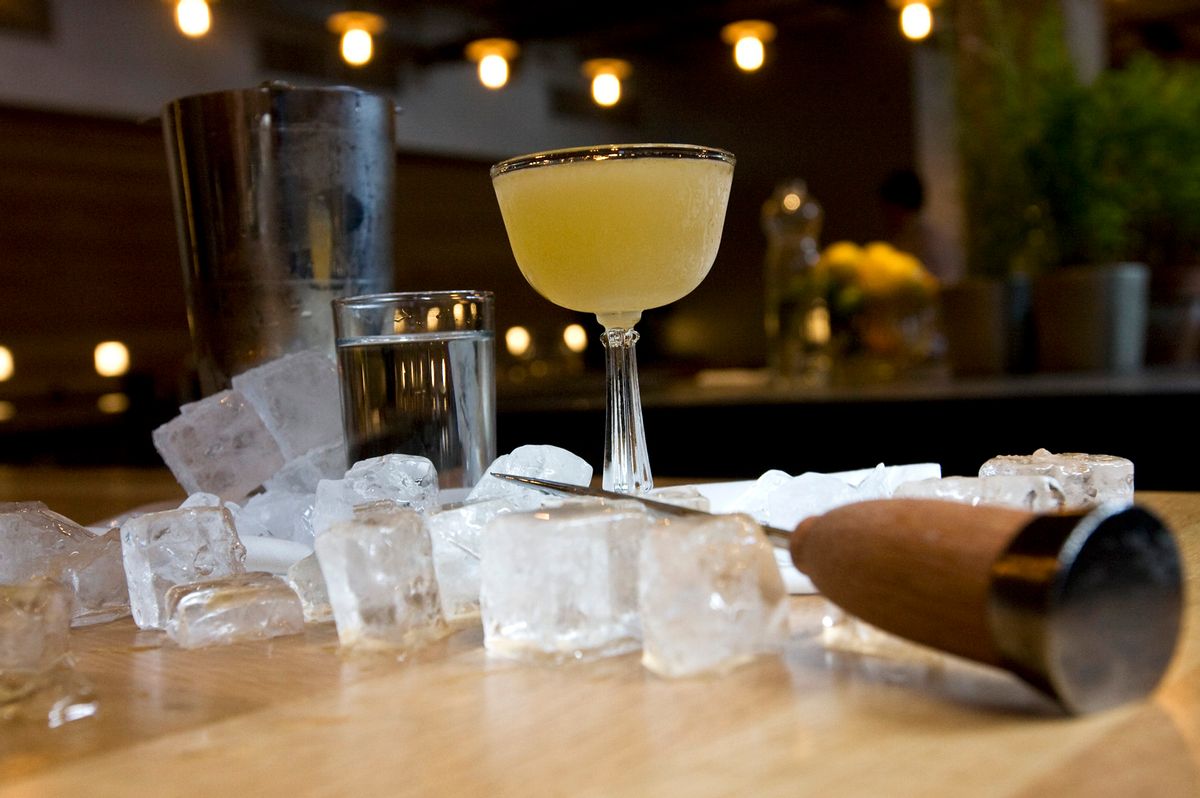 An alcoholic drink is surrounded by ice. A knife is lying partially on the ice.
