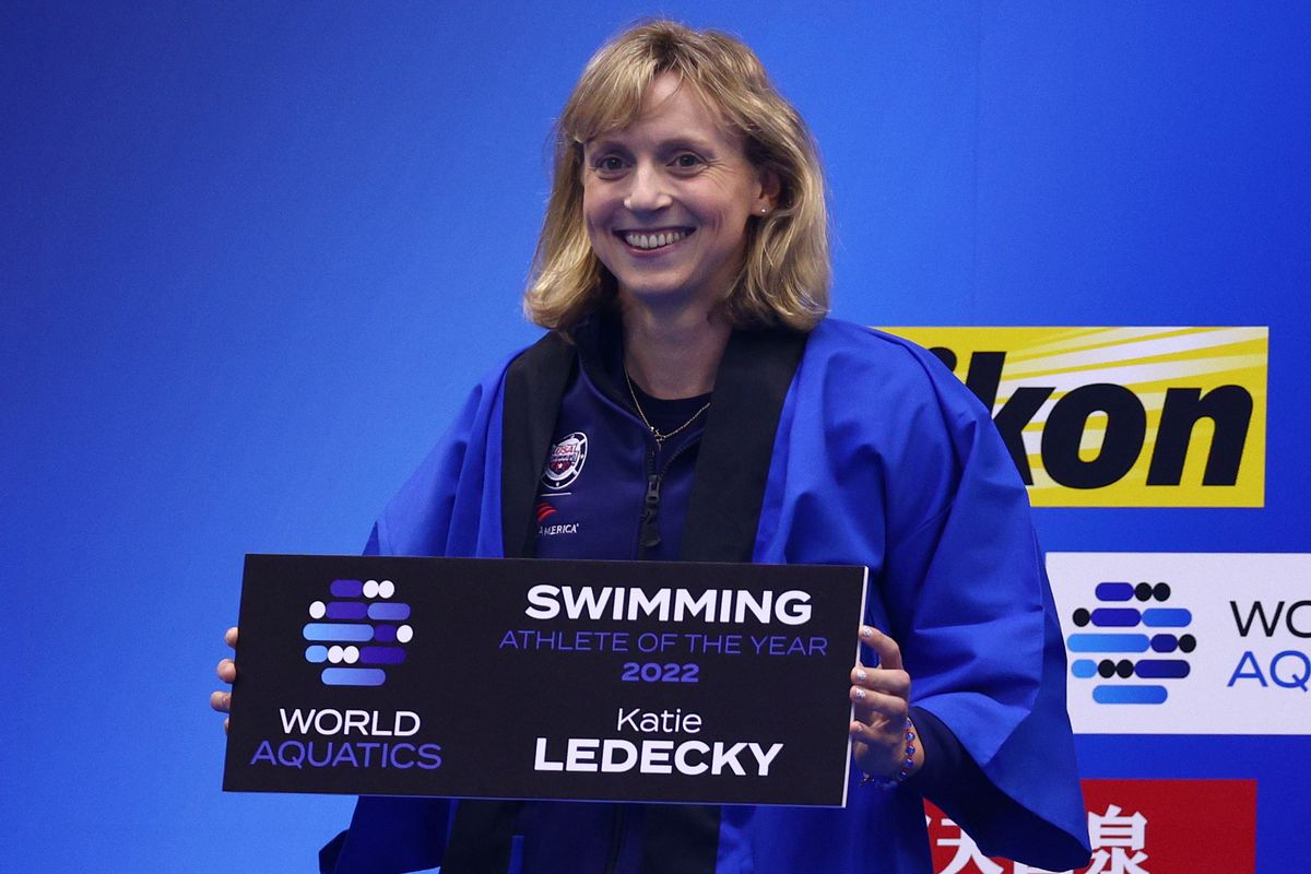 A blonde woman holds a sign that says World Aquatics  Swimming Female Athlete of the Year 2022. Her name, Katie Ledecky, is printed at the bottom of the sign.