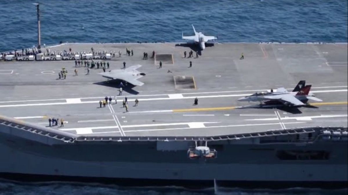 Three planes are on a large ship. People are also on the ship, with many gathered towards the left side of the boat.