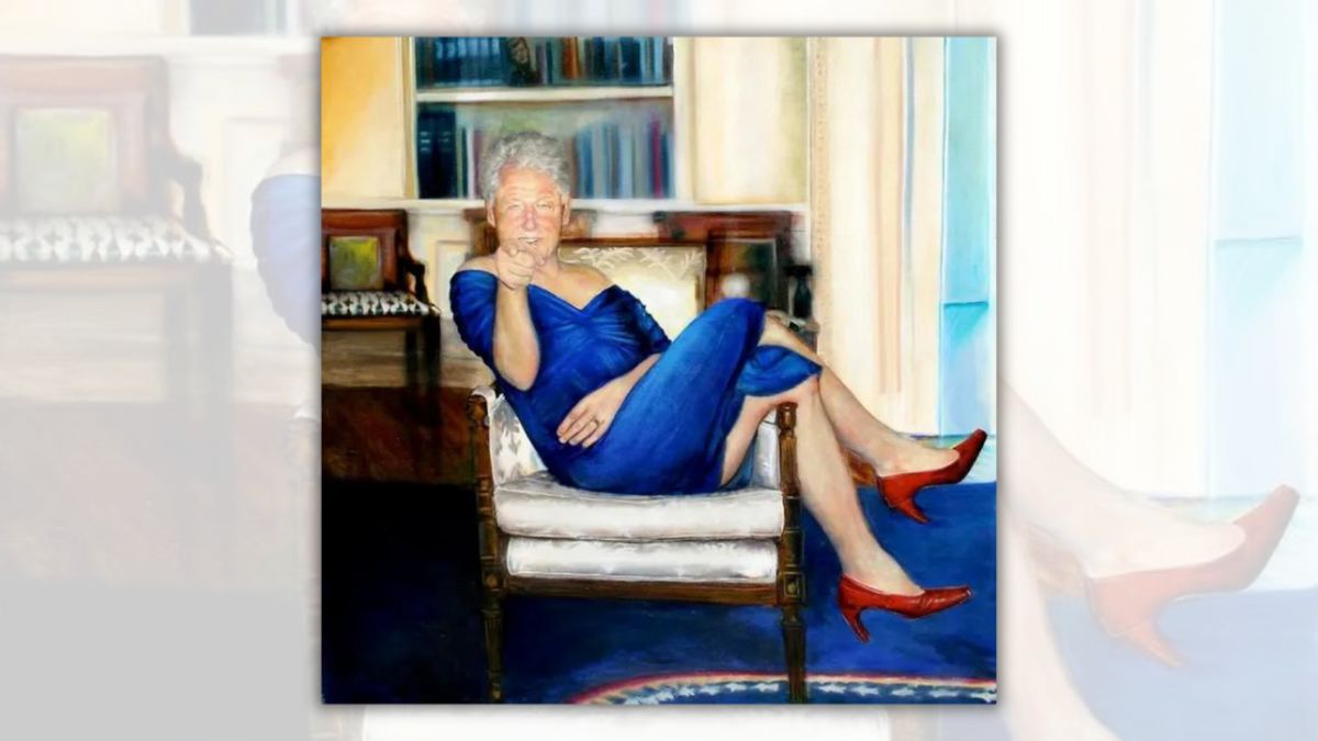 A white man in a blue dress sits in a chair, with his red heals over the right arm of the chair.