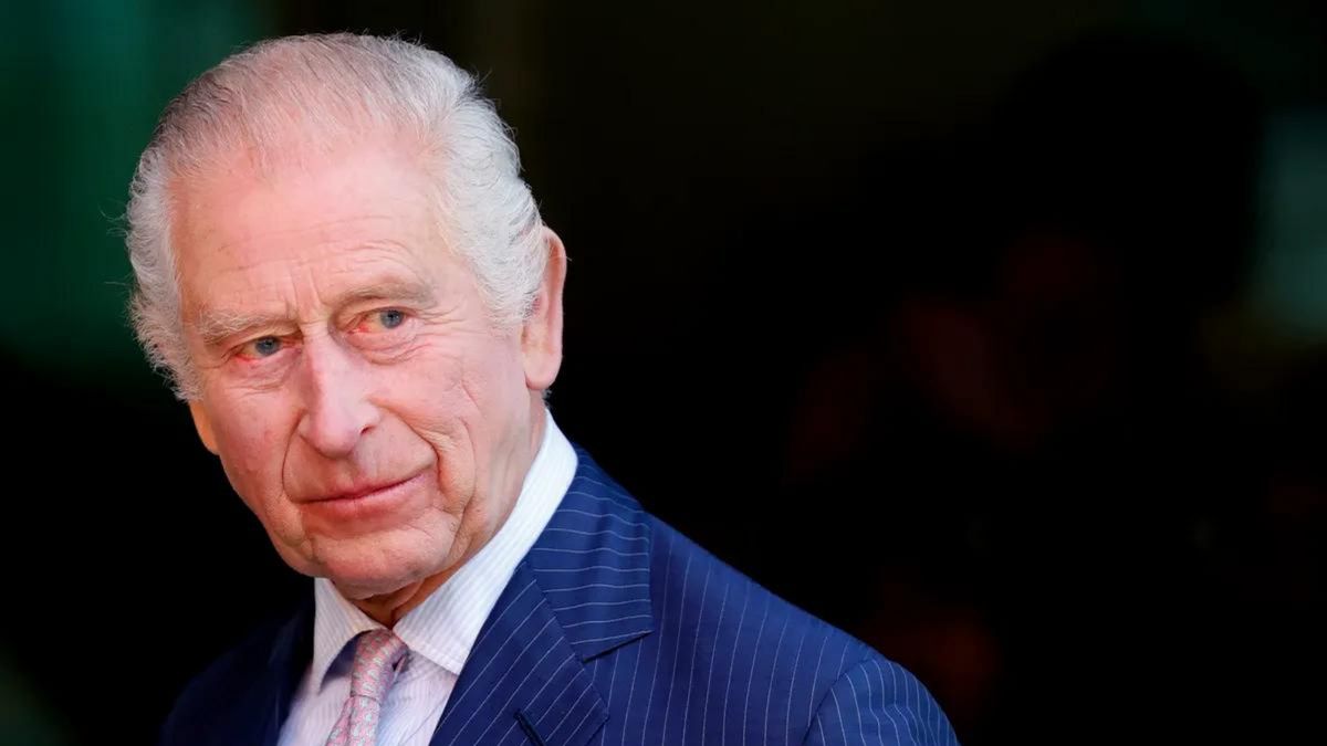 A white man wearing a blue suit looks straight ahead.