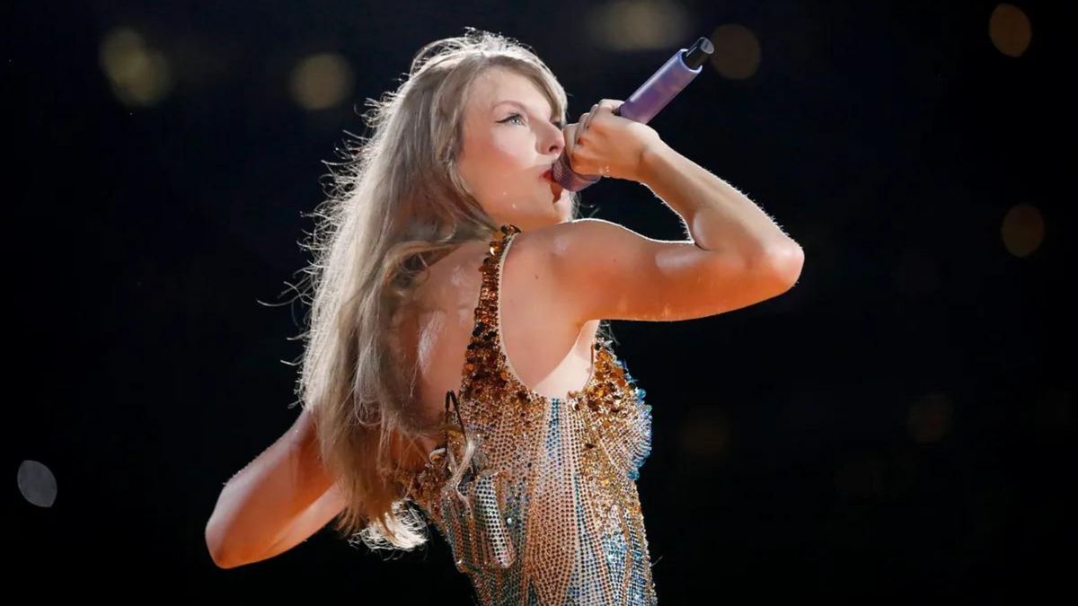 A white woman sings into a purple microphone.