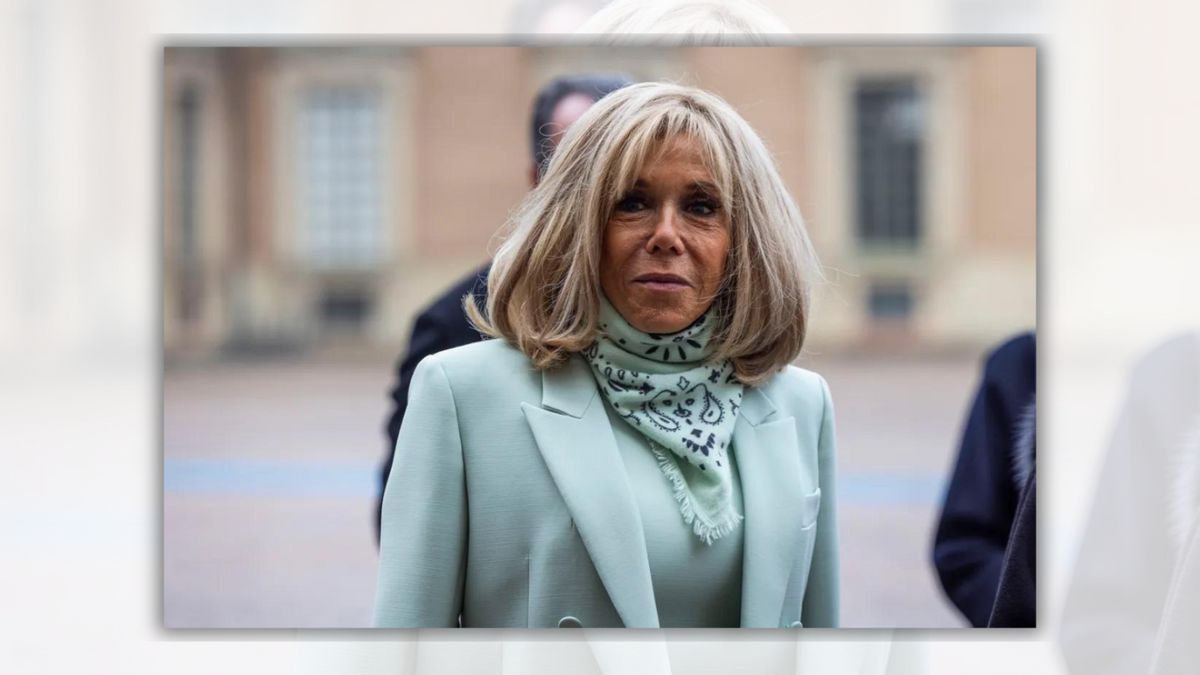 A white woman wearing a blue suit and bandanna scarf looks towards the camera.