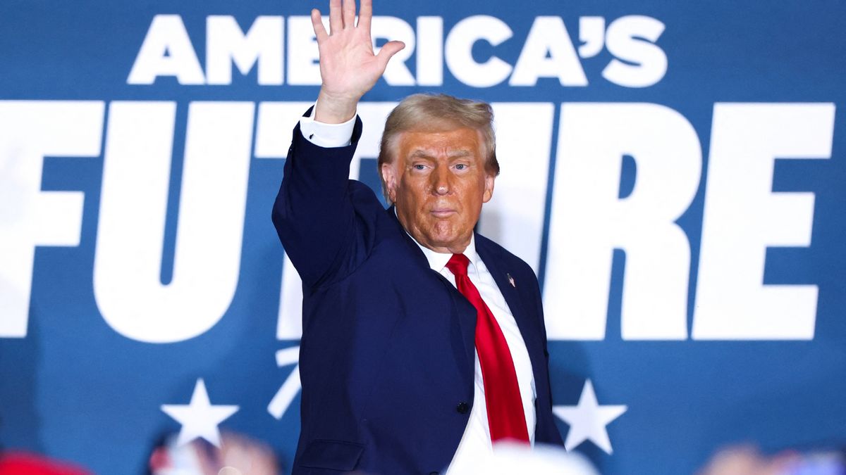 A white man wearing a blue suit raises his left hand in greeting. Large white letters that say "AMERICA'S FUTURE" are behind him.