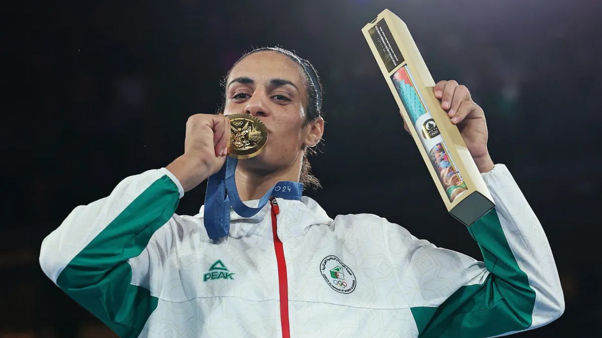 An Algerian woman kisses a gold medal while looking at the camera.