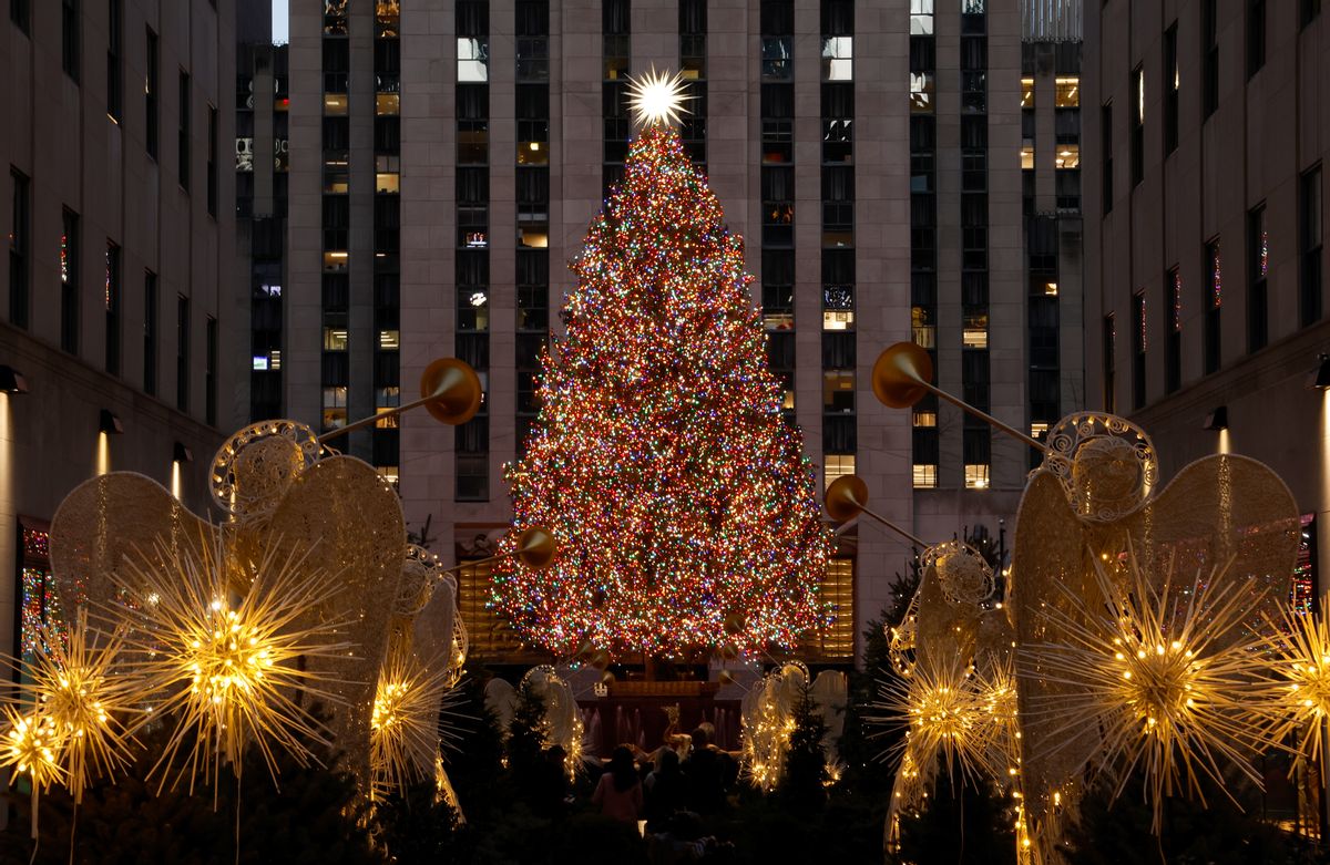 A Christmas tree decorated with red, white and gold lights is surrounded by gold decorations. A gold star is at the top of the tree.