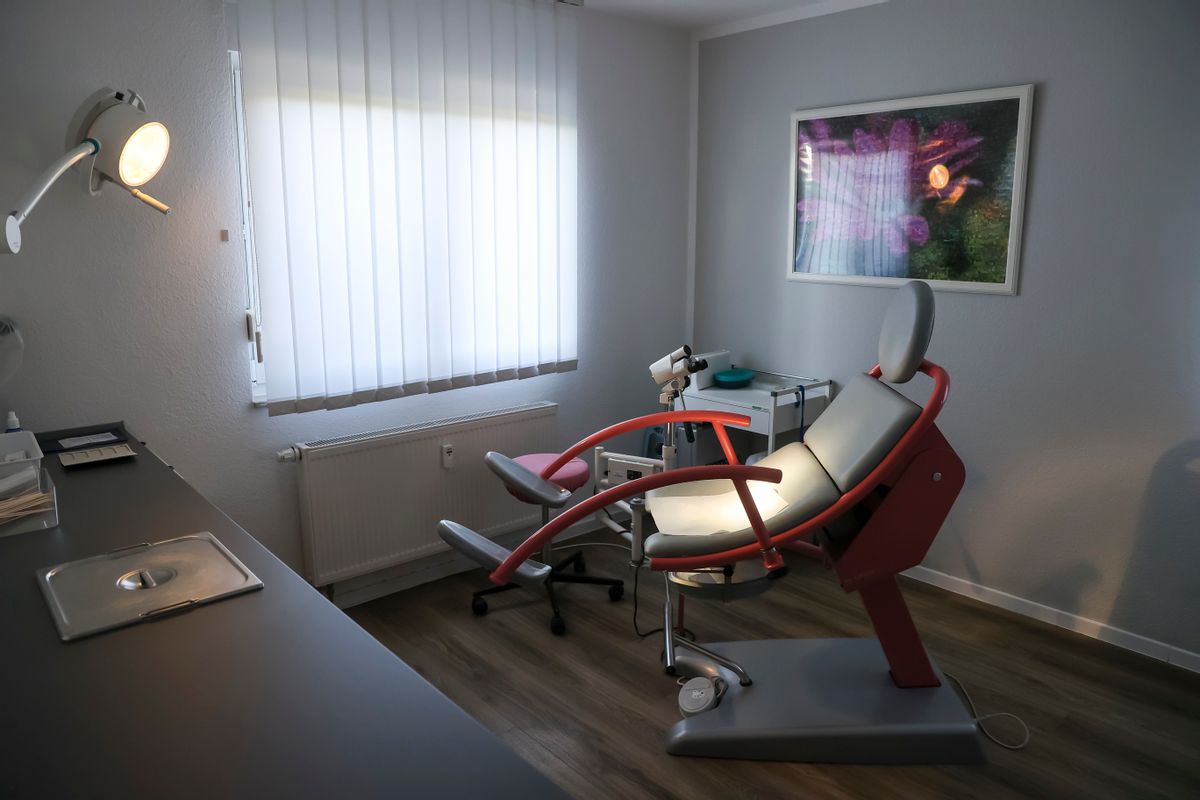 An empty gynecology chair with footholds sits in an office.