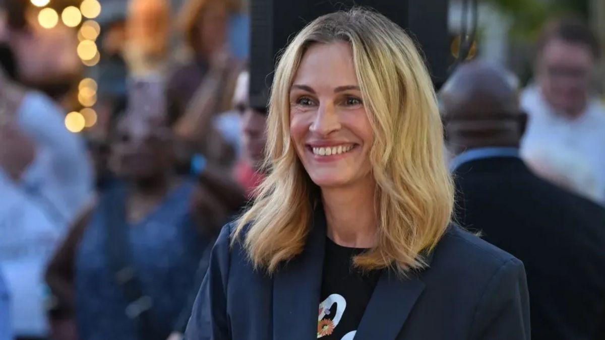 A white woman with blond hair smiles amongst a crowd of people.