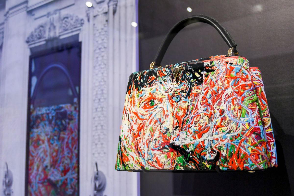 A handbag that colorfully shows a face is held on display inside a room.