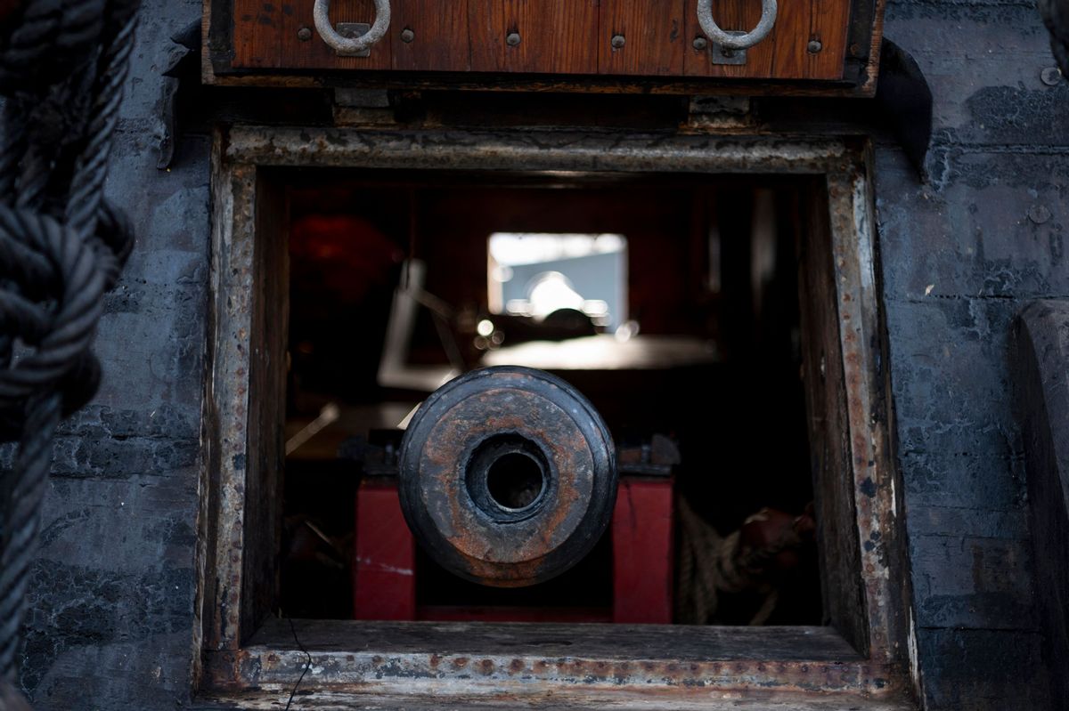 A cannon can be seen in a room that looks to be the interior of a ship.