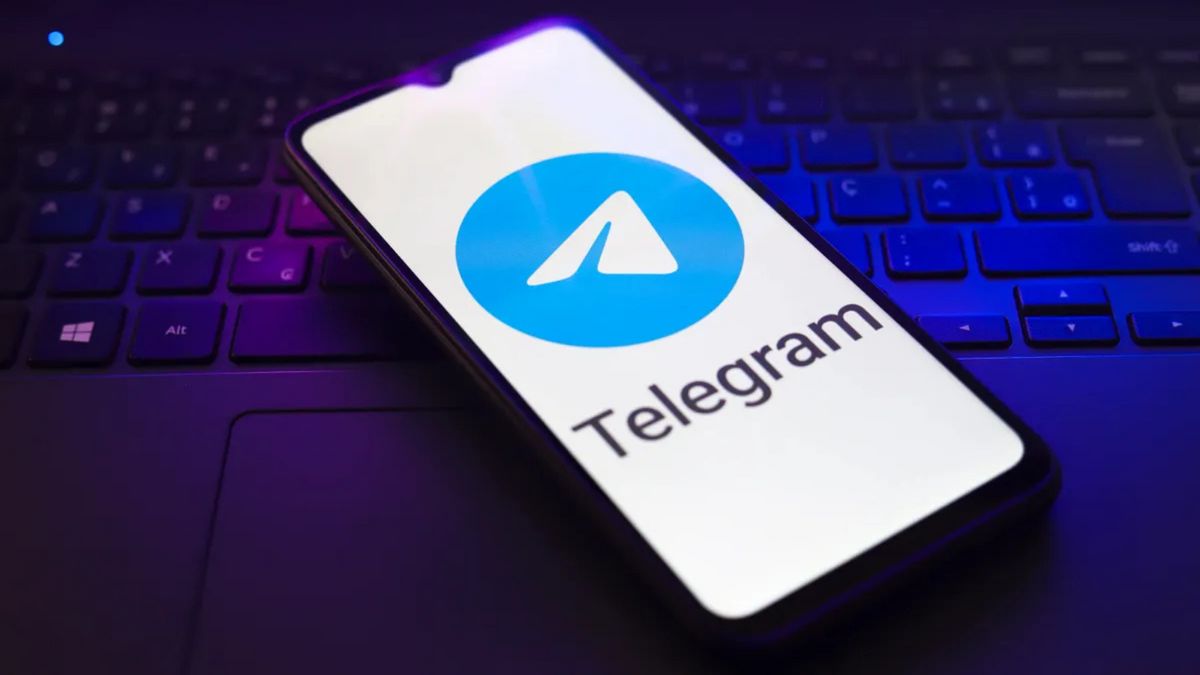 A phone shows a blue arrow in the center of a blue circle. The word Telegram is below. The phone itself is sitting on a purple keyboard.