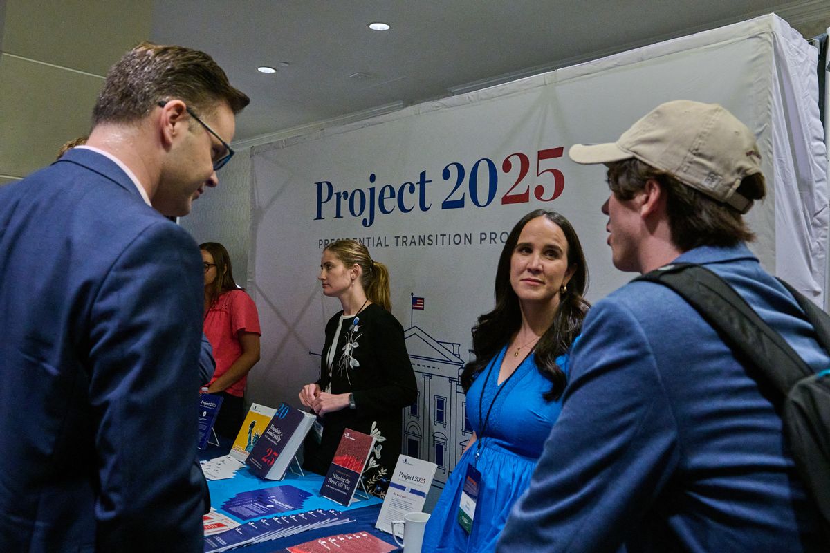 A group of people stand at a booth with a large "Project 2025" sign. 