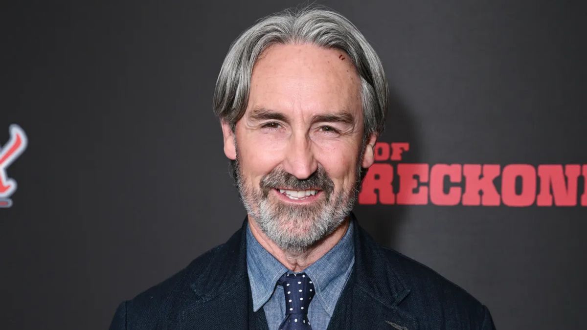 A white man smiles looking at the camera.