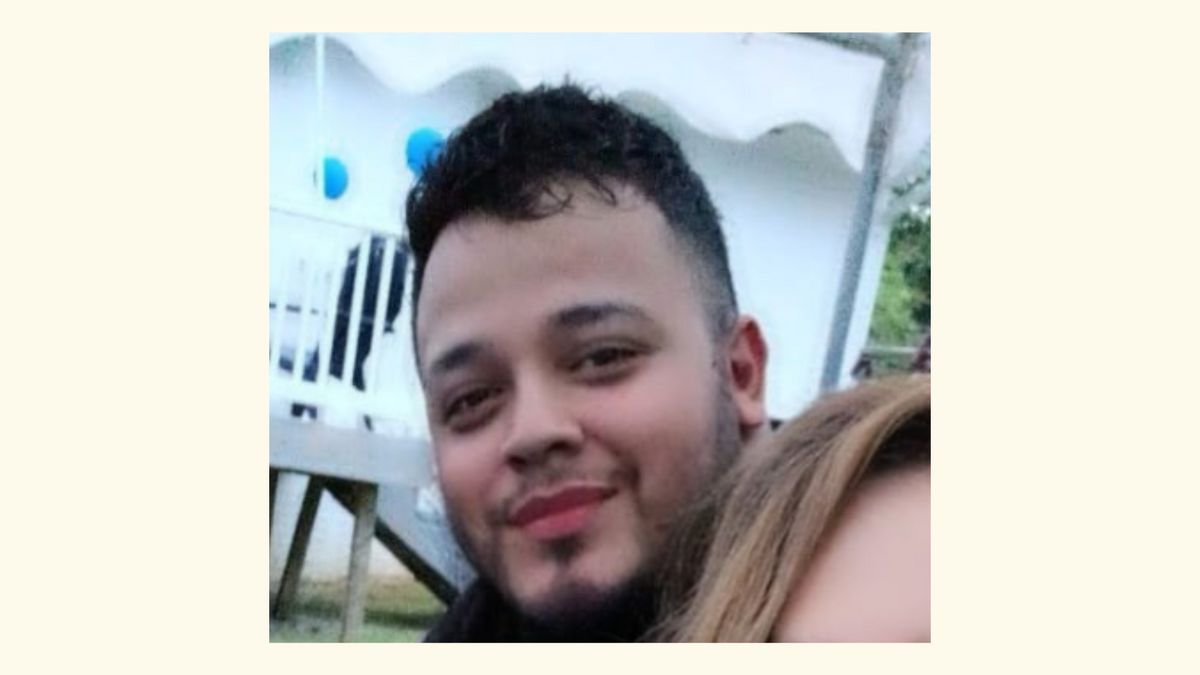 An image of a Latino man with short curly black hair shaved on the sides and a short mustache and beard smiling at the camera. 