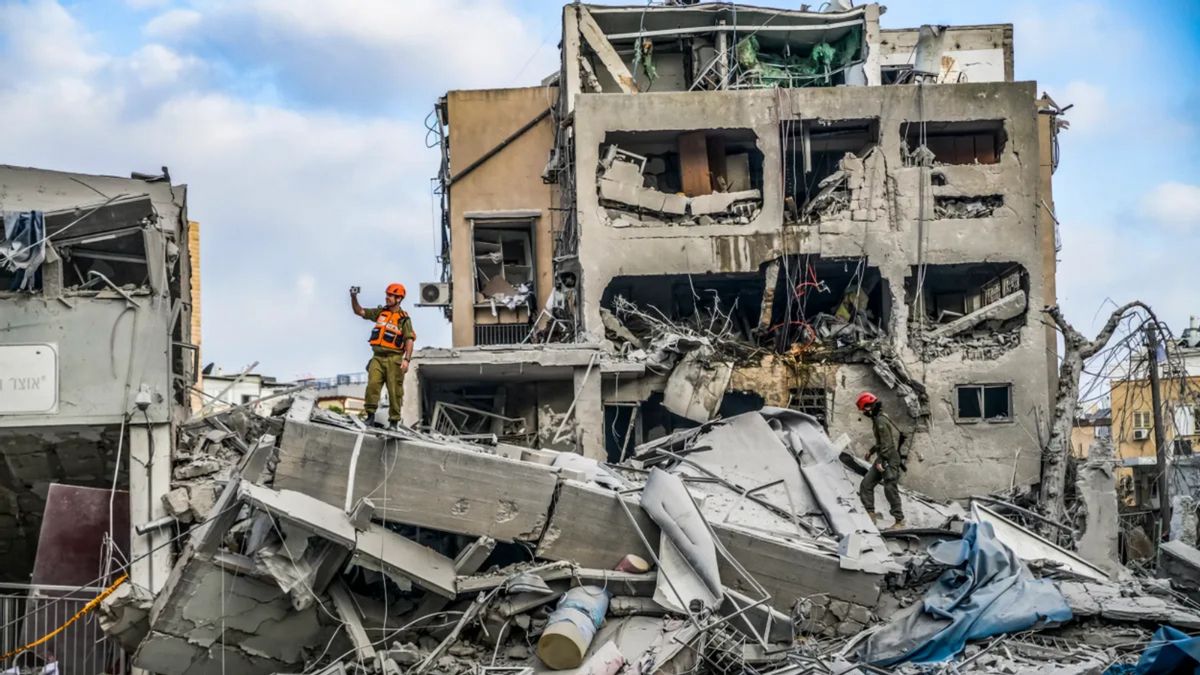 People stand on debris of buildings outside.