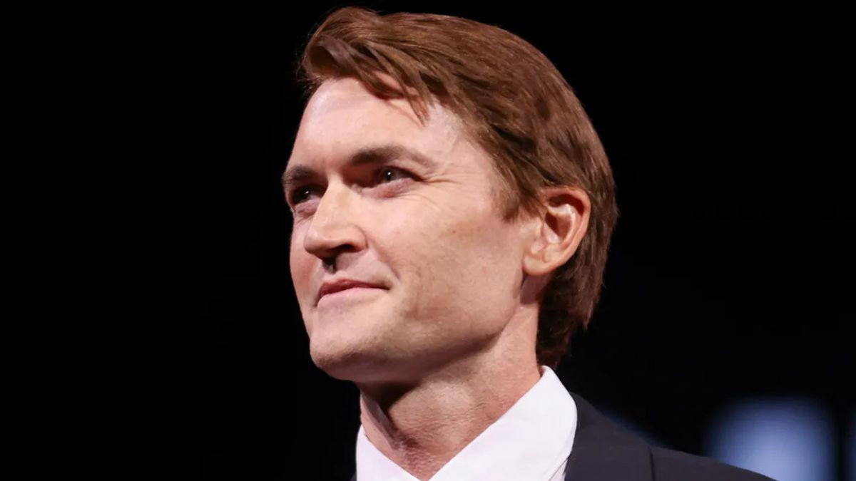 A white man wearing a dark suit looks to the left.