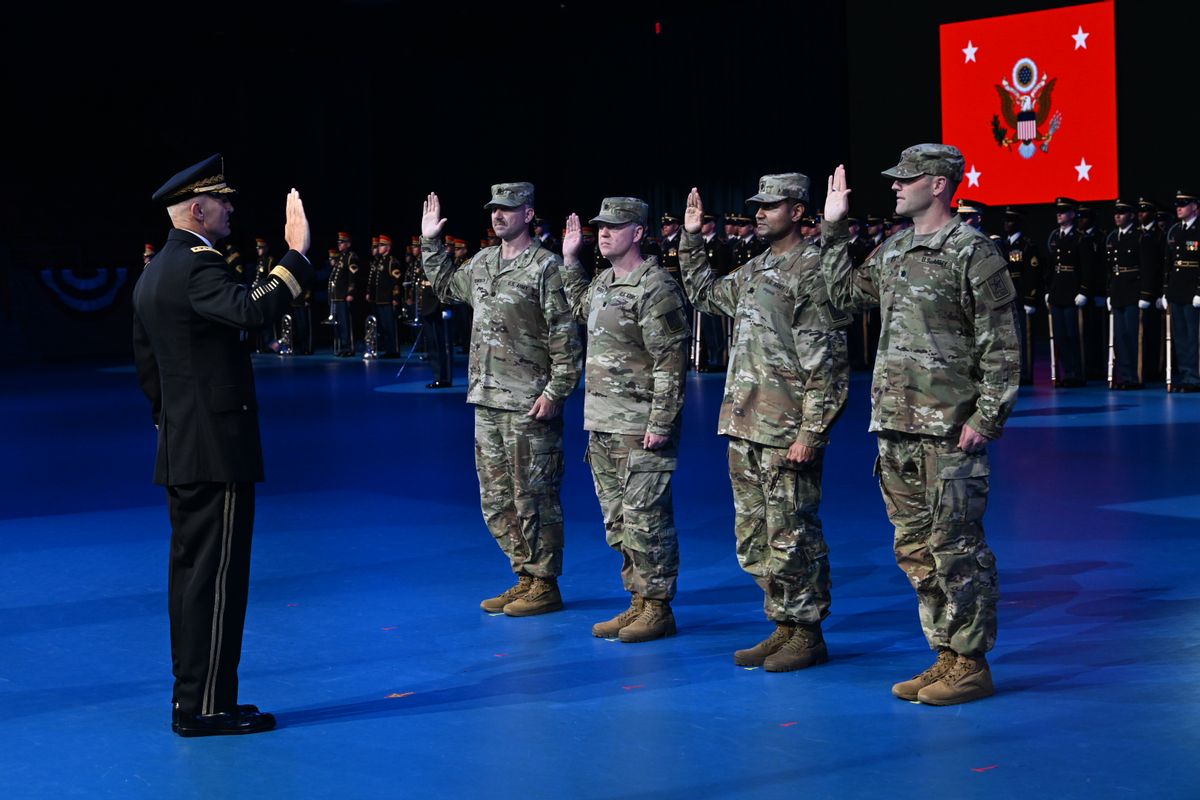 Four men in camouflage uniforms stand with their palms raised to swear an oath in front of one man in a military officer uniform who also has his palm raised.