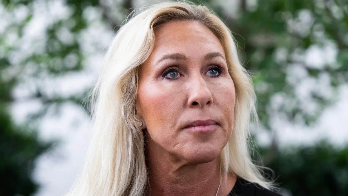 A white woman looks to the right while standing outside.