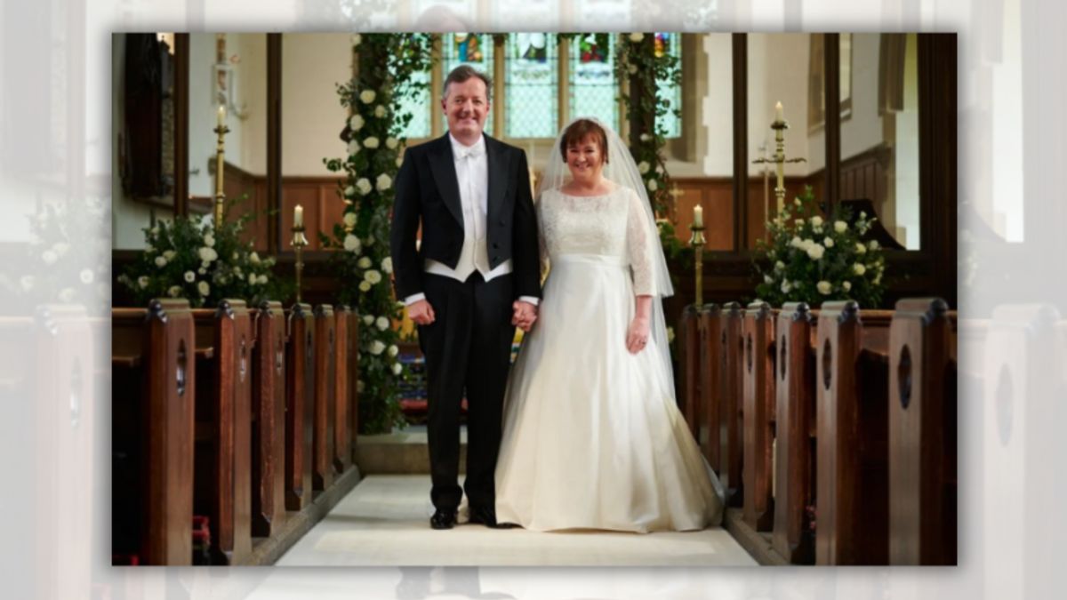 A white man and woman stand next to each other in a church. The man is wearing a black and white tuxedo, while the woman is wearing a long white dress and veil.