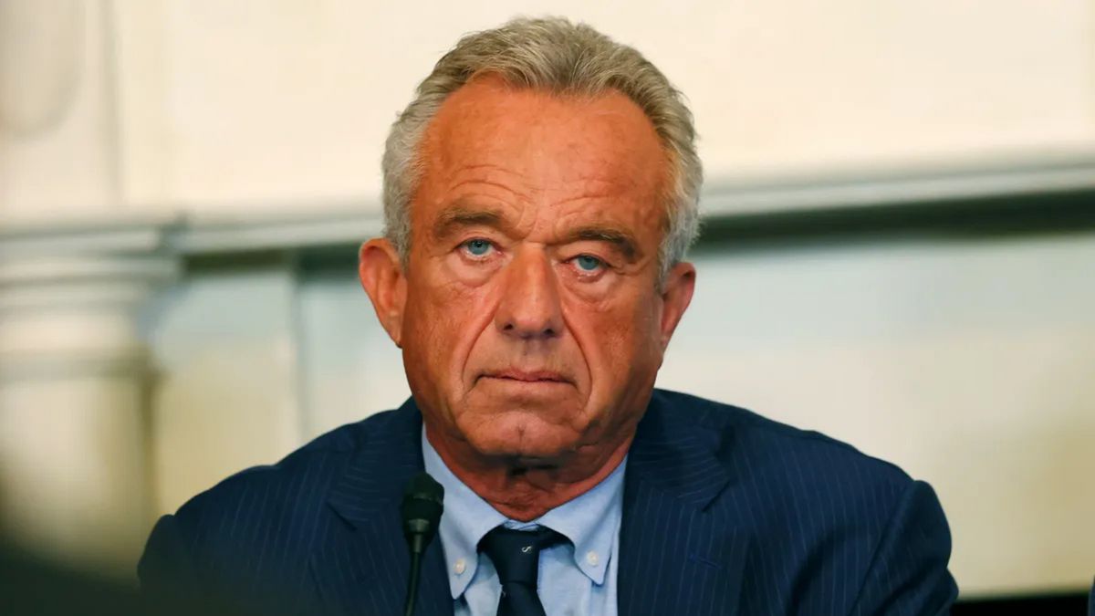 A white man wearing a blue suit looks at the camera.