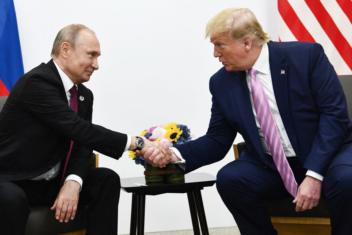Russian President Vladimir Putin, a balding white man, shakes hands with U.S. President Donald Trump, a white man with short white-blonde hair.