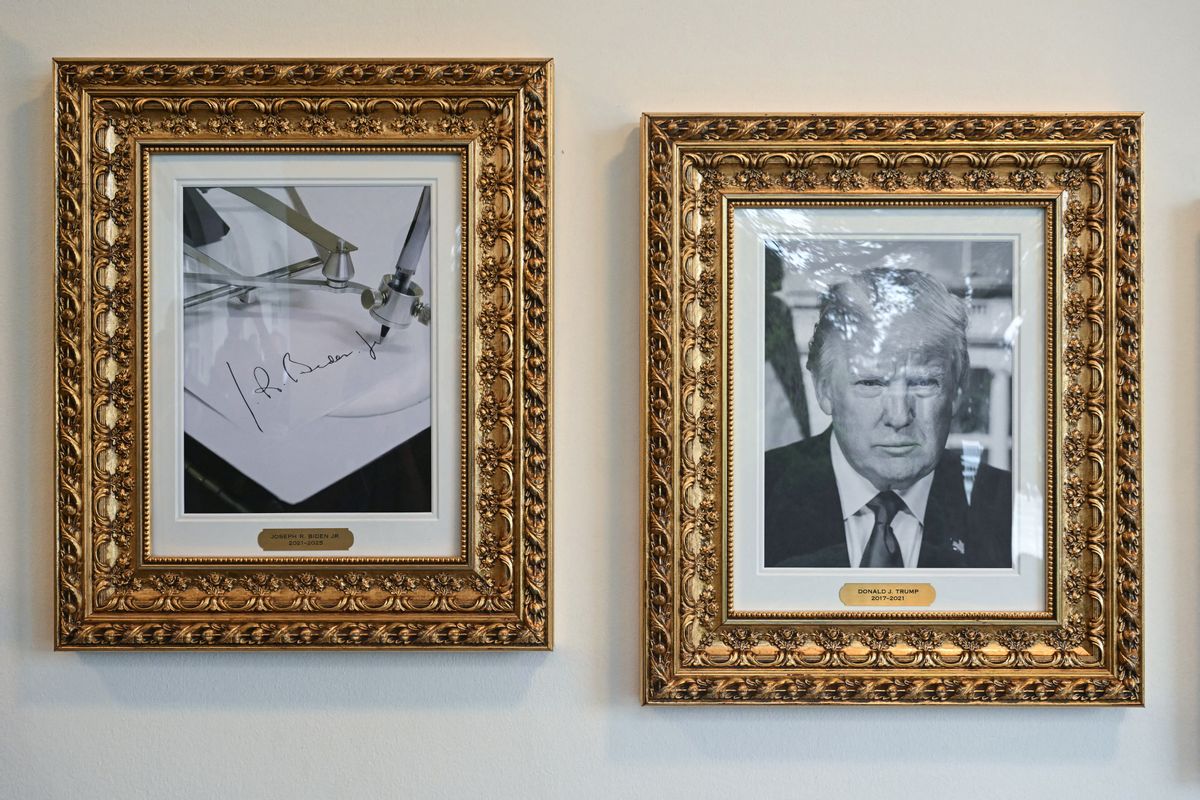 Two black and white portraits in gold frames. The portrait on the left is labeled "Joseph R. Biden" and shows a photo of a machine signing Biden's name. The portrait on the right is a headshot of U.S. President Donald Trump. 