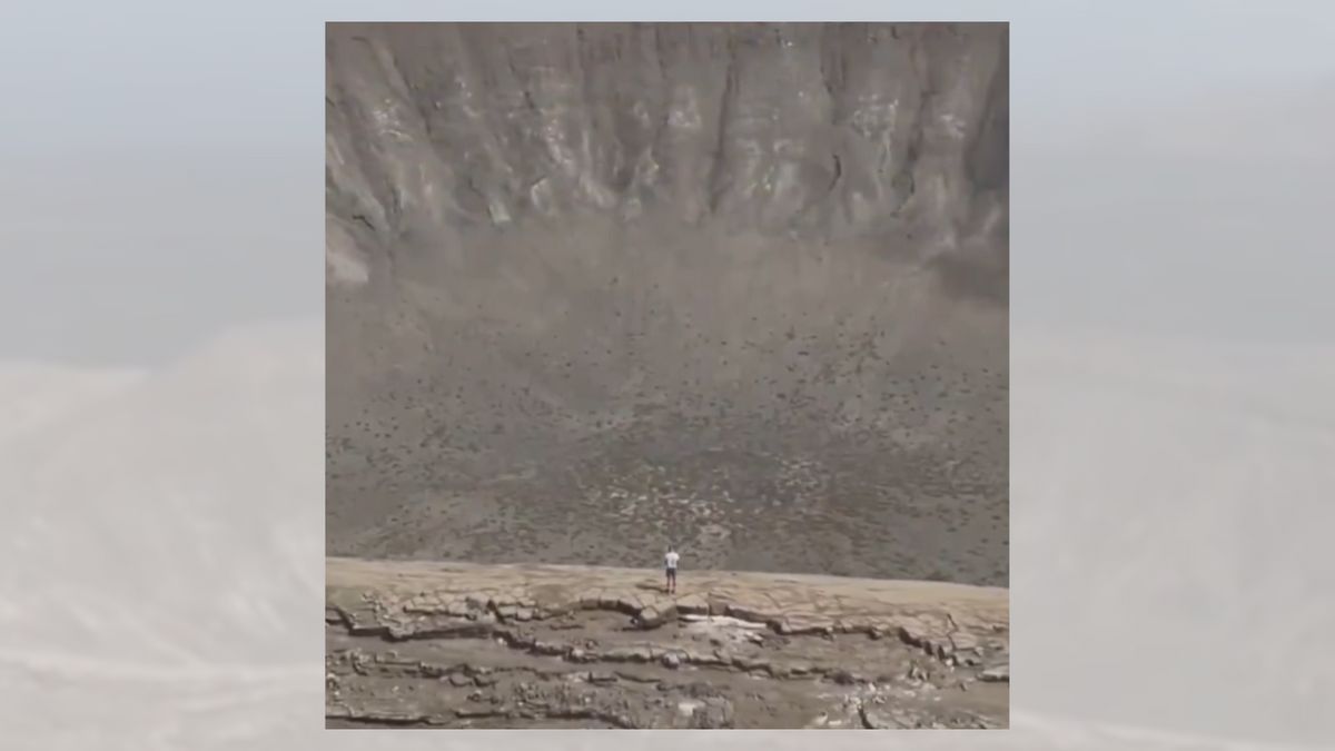 A person stands in front of a huge crater.