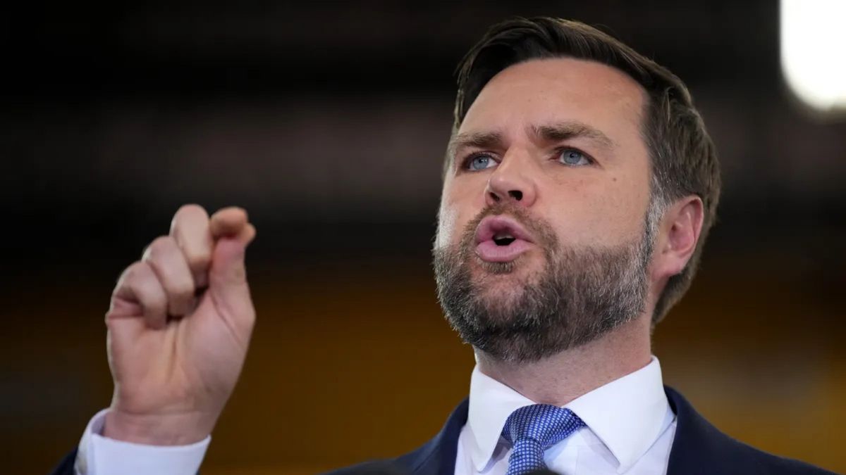 A white man wearing a black suit speaks.