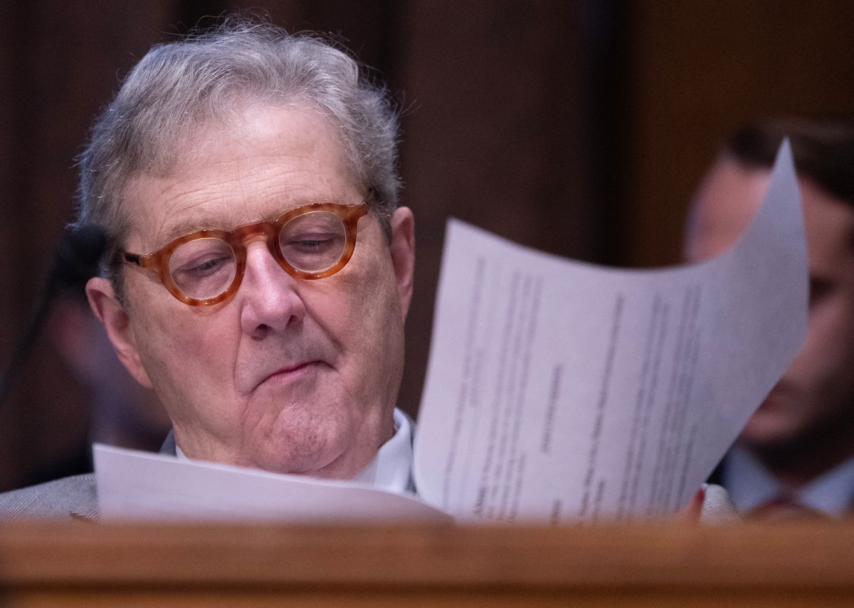 An older white man wearing circle glasses sifts through papers. 