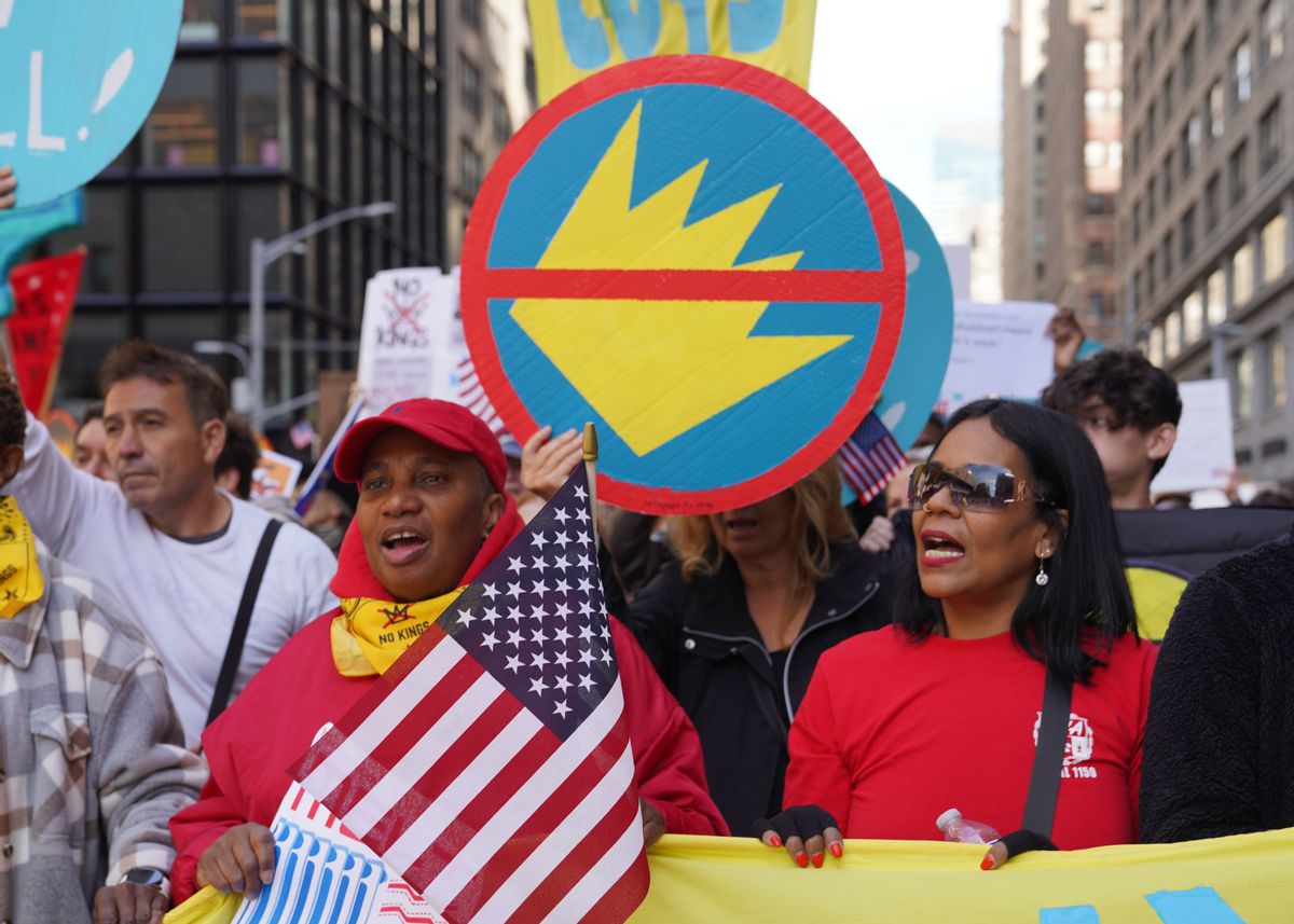 Protesters hold US flags and signs with a crown crossed out. 