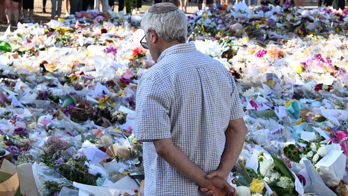 A man looks at a large amount of remembrances. He is facing away from the camera, with his arms around his back.