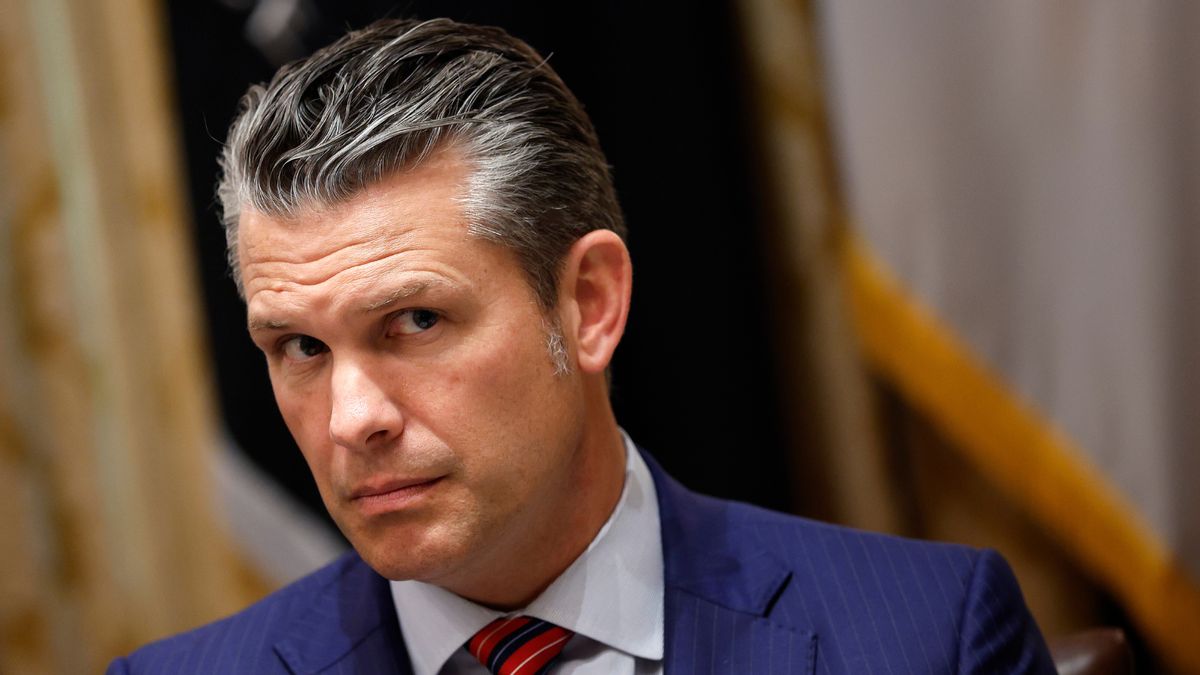 A white man wearing a dark blue suit looks towards the right.