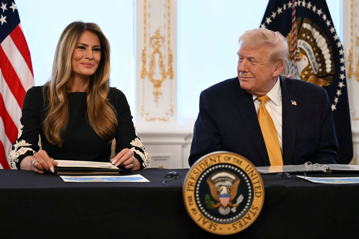 Melania Trump and U.S. President Donald Trump seated at a table, smiling. 
